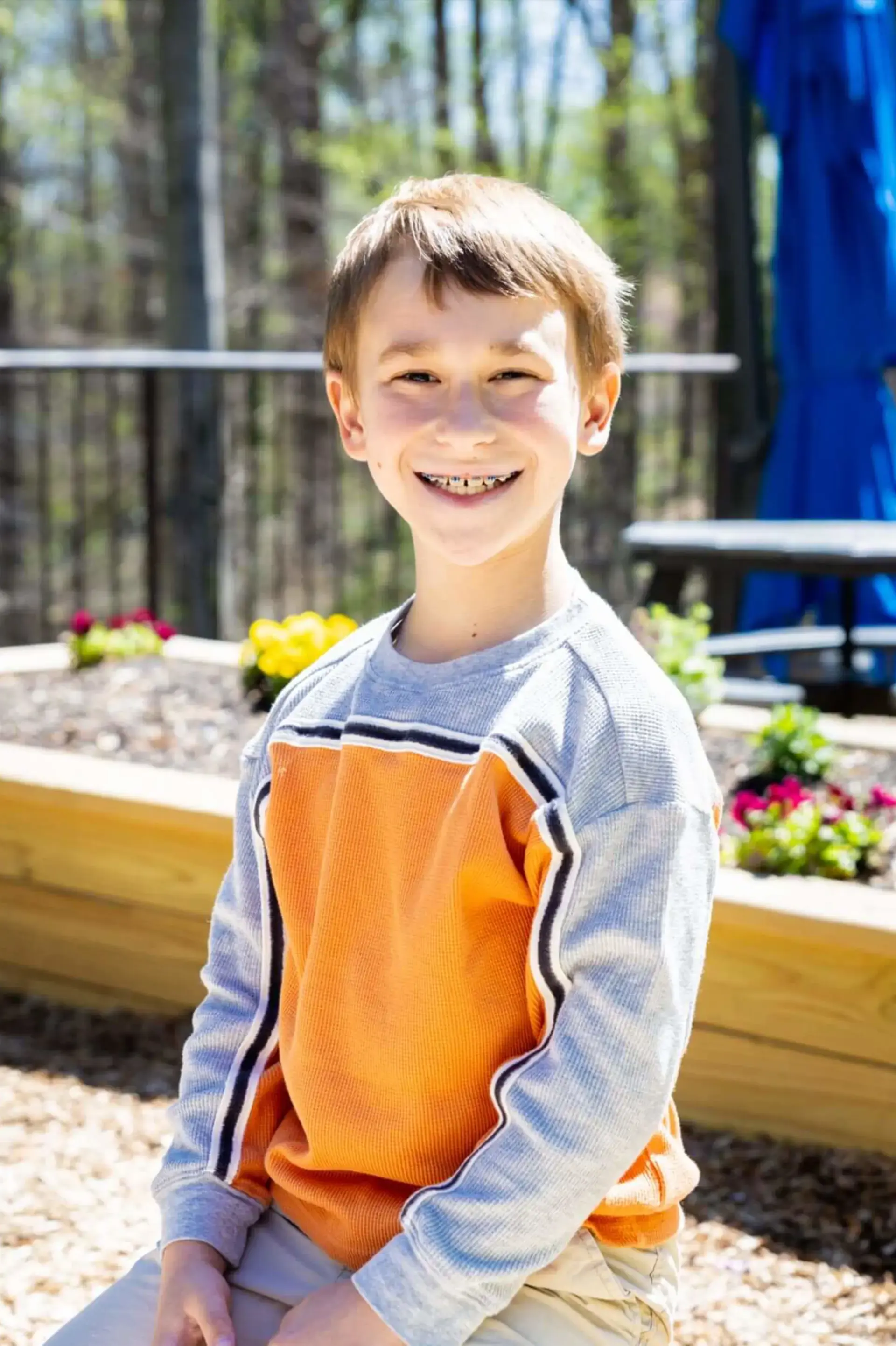 Student kneeling in garden, smiling up at camera