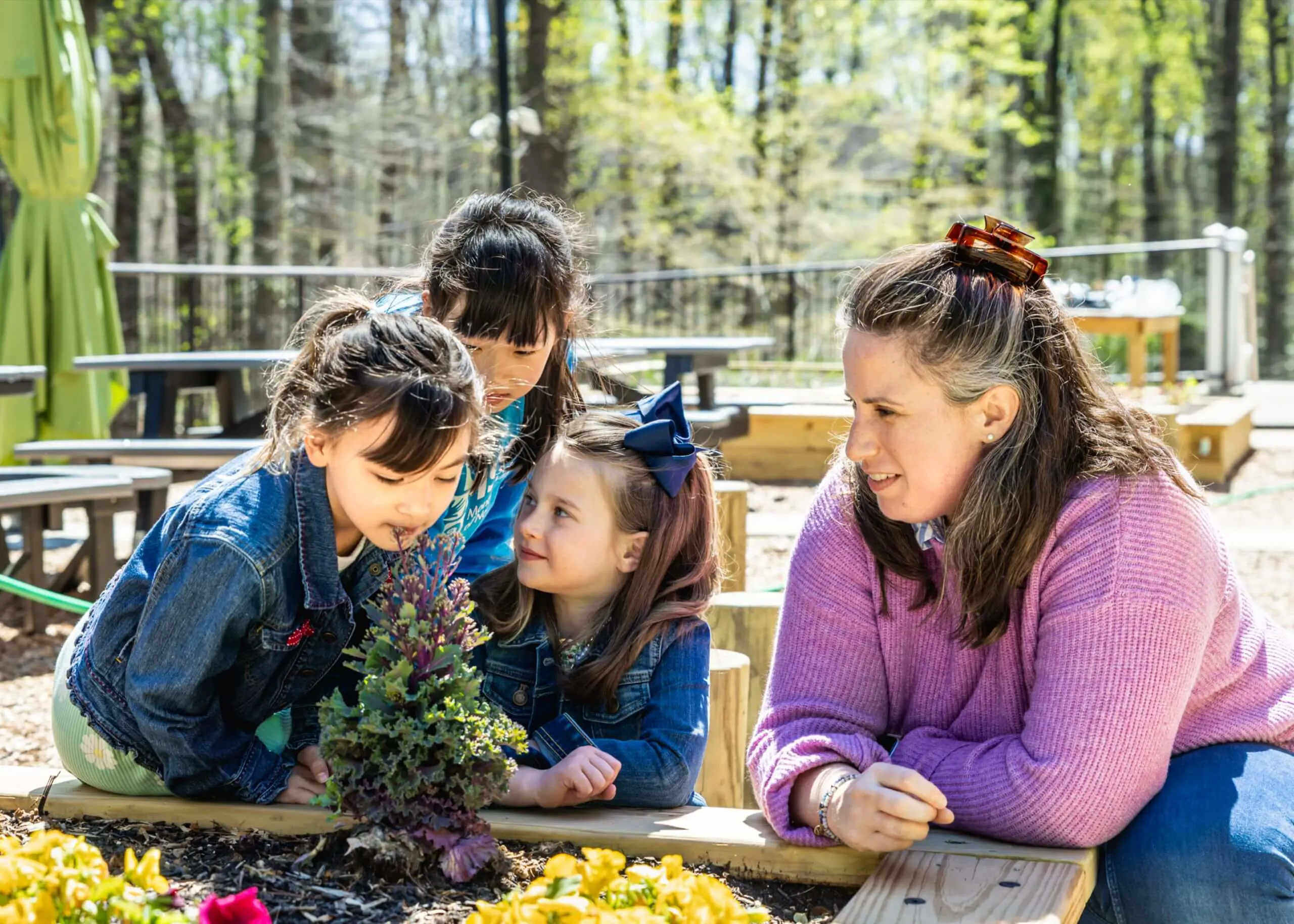 Three MSNV Elementary students collaborating on an outdoor nature study or science activity at a table.