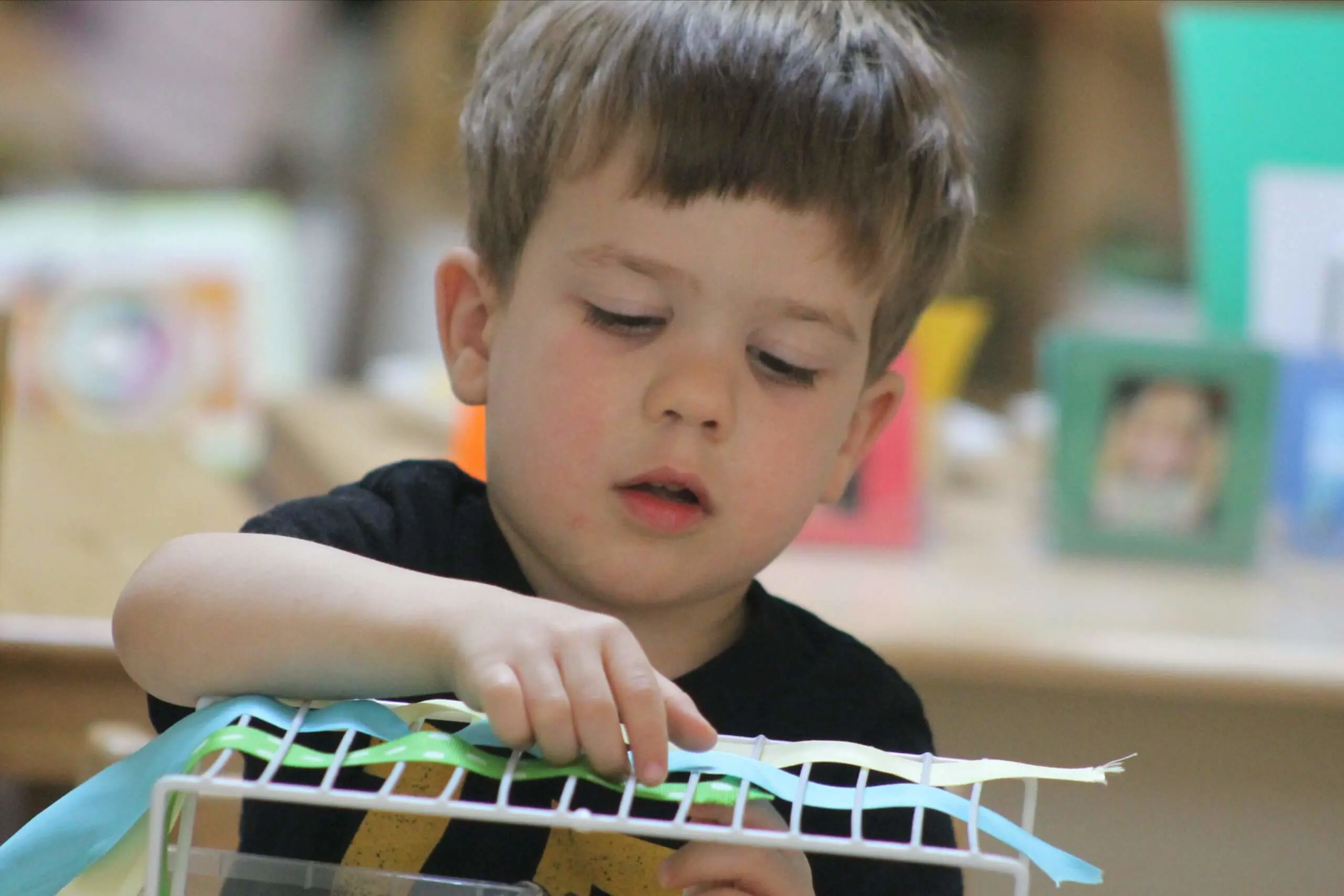 A young MSNV student carefully working building something at a classroom table.