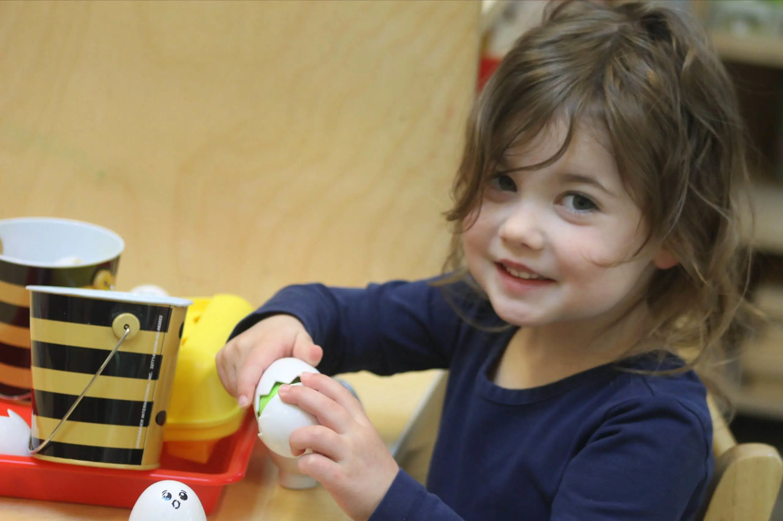 A young MSNV Primary student carefully working with Montessori materials at a classroom shelf.