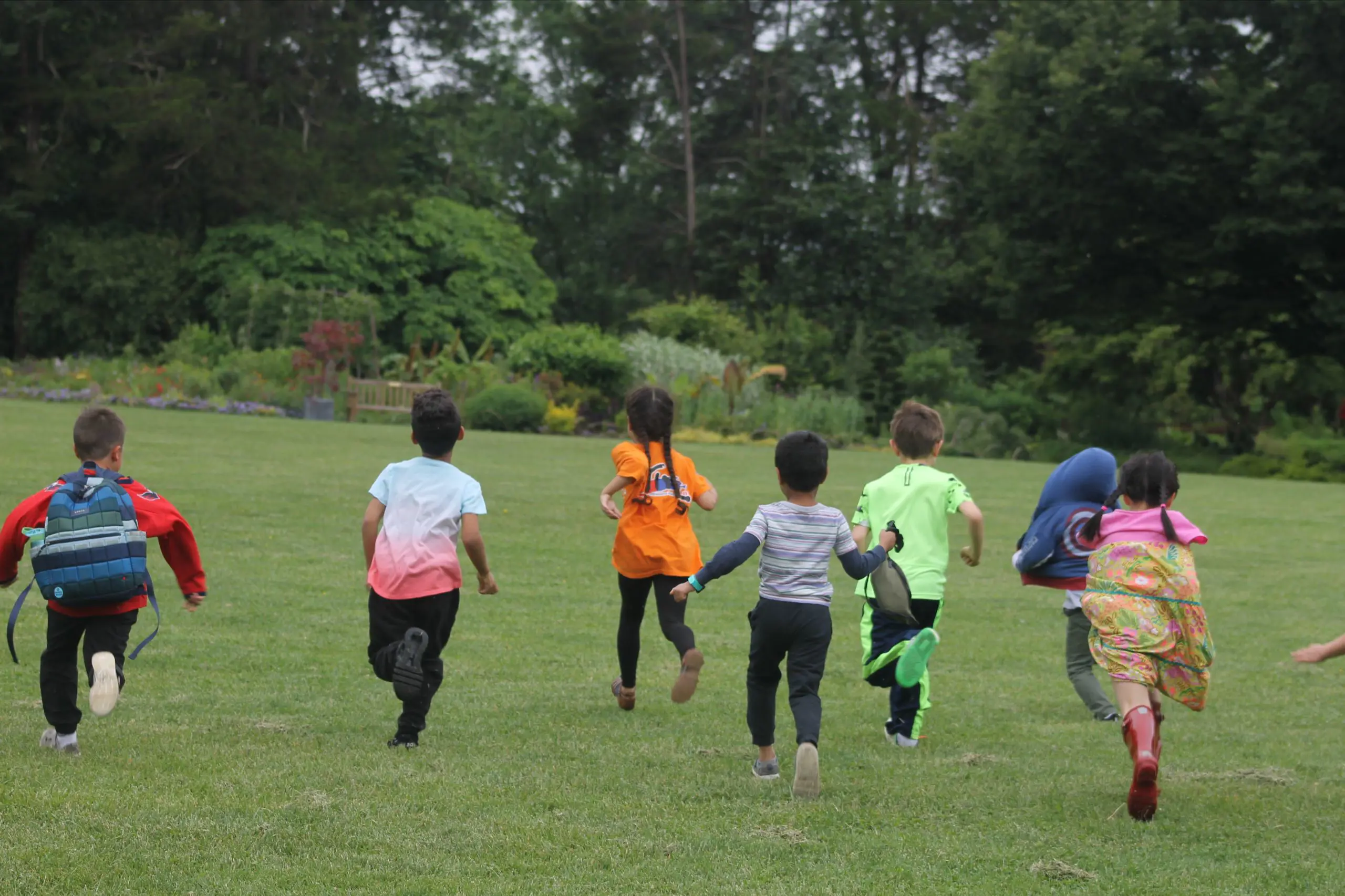 A group of MSNV students running together across a grassy field on a school outing.
