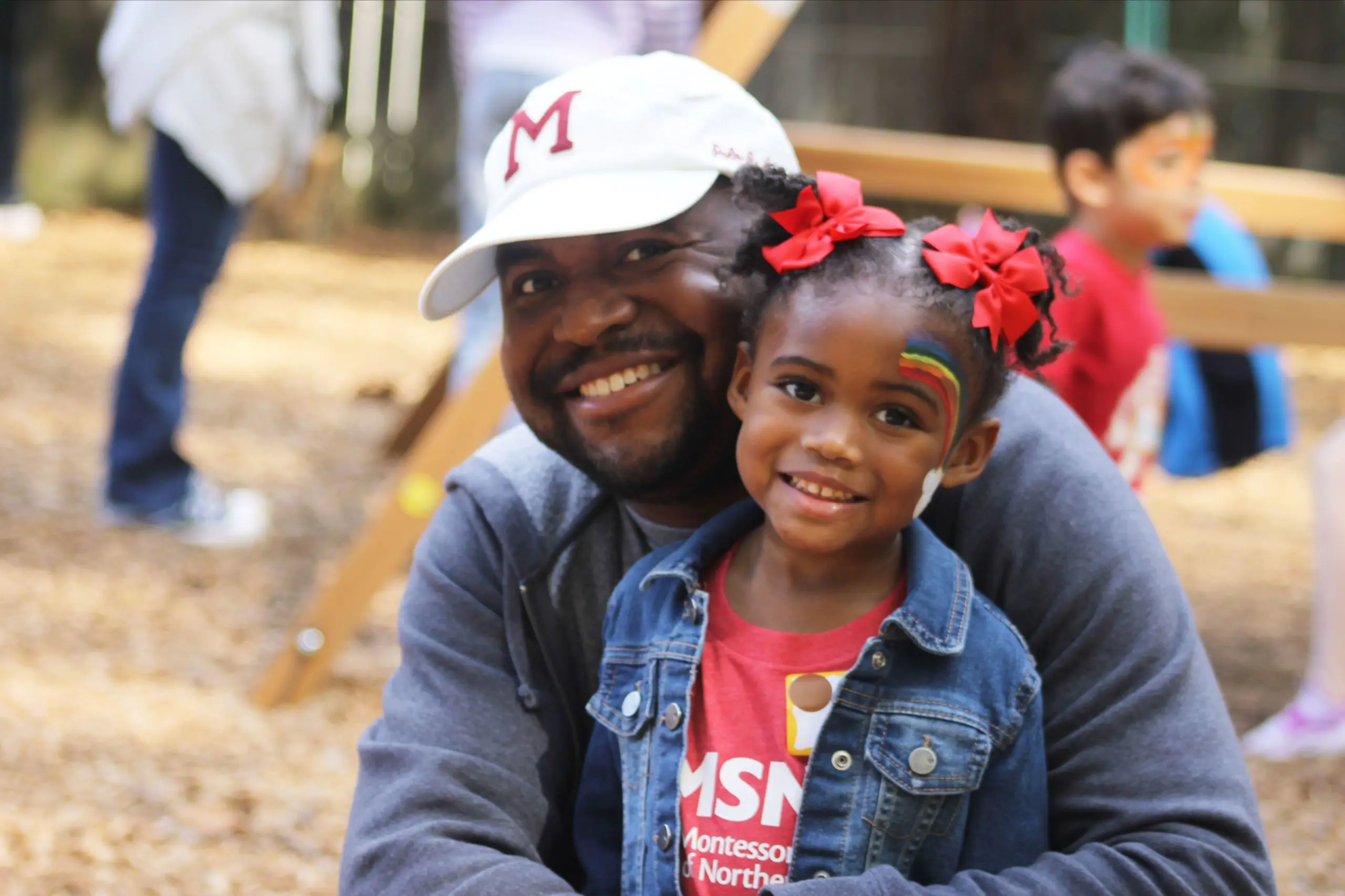 A father and young daughter smiling together outdoors at an MSNV fall festival.